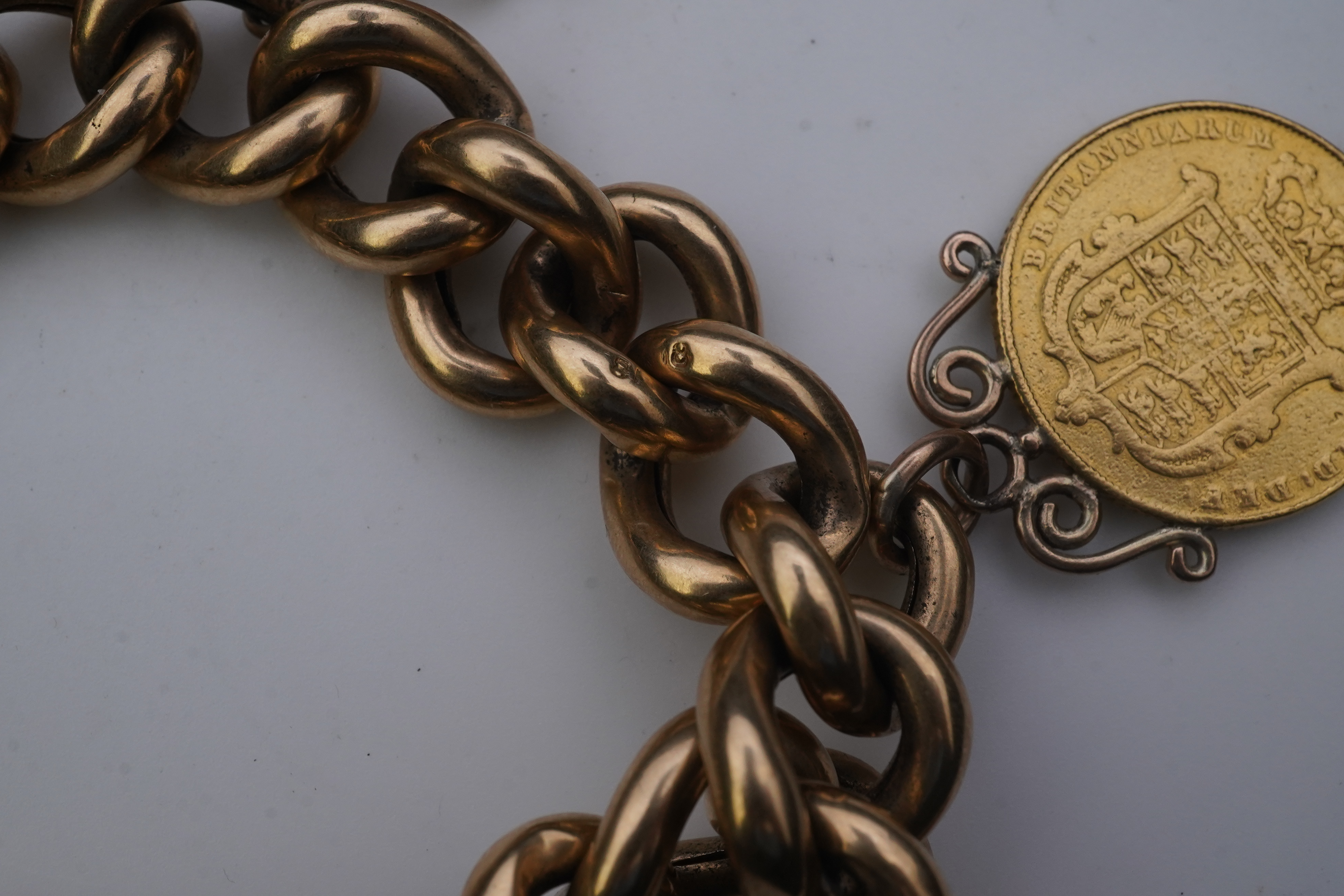 An Edwardian 18ct gold charm bracelet and five gold coin pendants